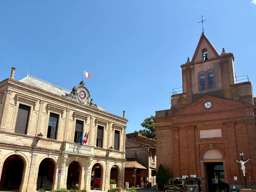 La mairie et l'église en brique de Montastruc-la-Conseillère, sous un ciel bleu